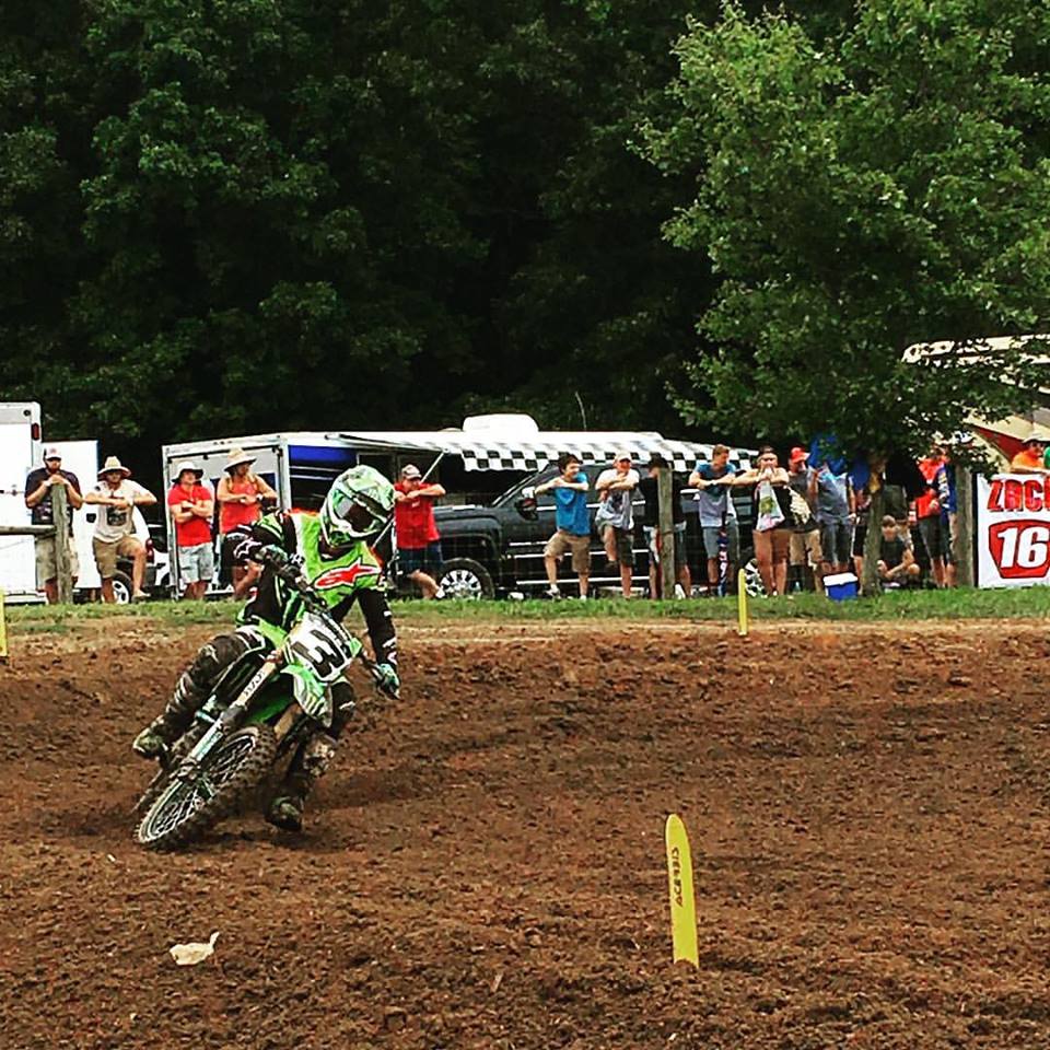 Eli Tomac on his number 3 Kawasaki leaning through a dirt turn with fans behind the fence